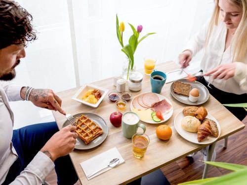 a group of people sitting around a table with breakfast foods at ibis Hotel Regensburg City in Regensburg