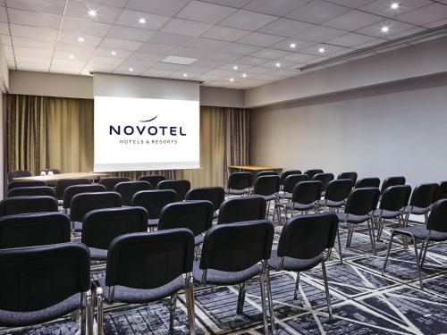 a conference room with chairs and a projection screen at Novotel Manchester West in Worsley