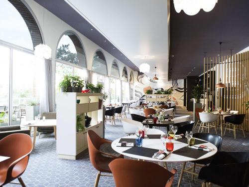 a restaurant with tables and chairs and windows at Novotel Toulouse Centre Compans Caffarelli in Toulouse