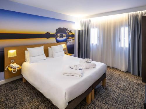 a bedroom with a large bed with towels on it at Novotel Toulouse Centre Compans Caffarelli in Toulouse