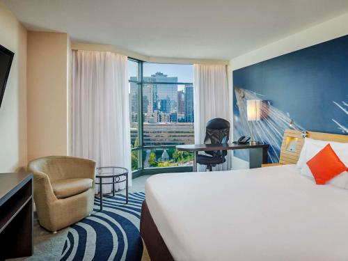 a hotel room with a bed and a chair and a window at Novotel Toronto North York in Toronto