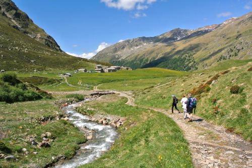 two people walking down a trail in the mountains at Hotel Nordik in Santa Caterina Valfurva