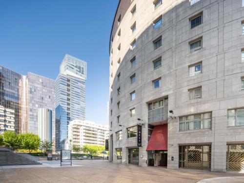 a large stone building in a city with tall buildings at Nest Hotel Paris la Défense - MGallery Collection in Puteaux