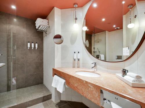 a bathroom with a sink and a mirror at Nest Hotel Paris la Défense - MGallery Collection in Puteaux