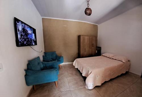 um quarto com uma cama e uma cadeira azul em Chácara Liberdade em Pirenópolis