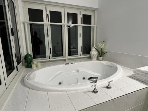 a white bath tub in a bathroom with windows at Island Romance or Family & Pool in Nelly Bay