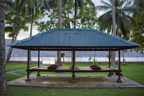 a bench with a blue roof in a park at Belongas Bay Lodge LOMBOK in Blongas