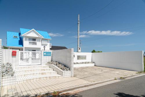a white house with a white fence and stairs at ゲストハウスKe'oKe'o in Higashikagawa