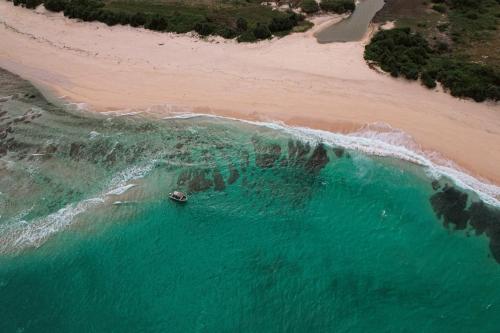 an aerial view of a beach with a boat in the water at Belongas Bay Lodge LOMBOK in Blongas