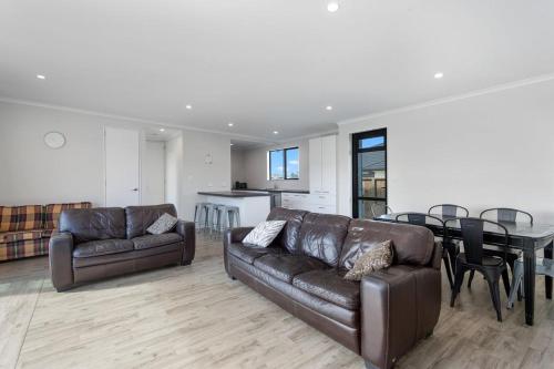 a living room with a leather couch and a table at Kukumoa At the Beach in Opotiki