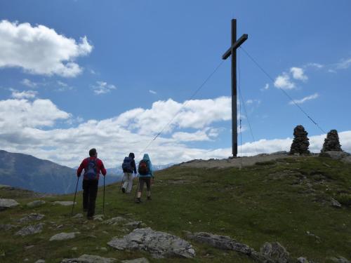 three people walking on a hill with a cross at Alpengasthof Norbertshöhe Superior in Nauders