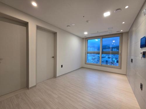 釜山にあるCentral Height Apartment Superiorの大きな窓が付いた空の広い客室です。
