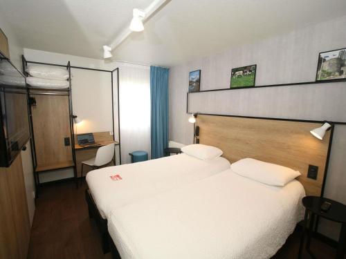 a hotel room with two beds and a desk at ibis Saint-Lô in Saint Lo