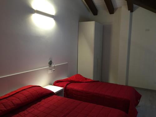 two beds in a room with red sheets at Dune Prestige & Chalets in Bibione
