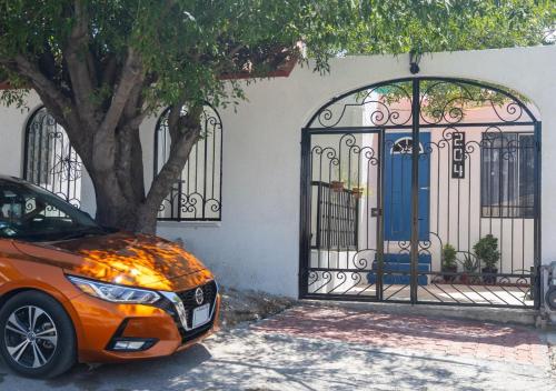 an orange car parked next to a building with gates at Genuina Inn, Tu Refugio Único, cerca de todo in Piedras Negras