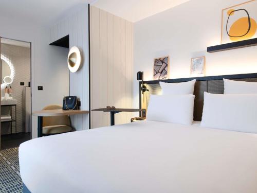 a bedroom with a large white bed with white pillows at Mercure Paris Bercy Bibliothèque in Paris