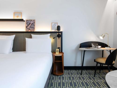 a bedroom with a bed and a desk and a table at Mercure Paris Bercy Bibliothèque in Paris