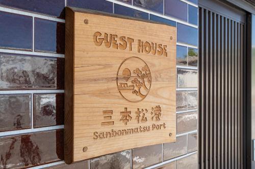 a sign for a guest house on a wall at ゲストハウス三本松港 in Higashikagawa