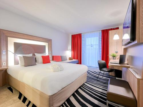 a hotel room with a large bed and a television at Novotel Paris Centre Bercy in Paris