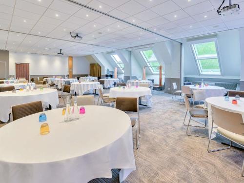 a room with white tables and chairs and windows at Novotel Paris Centre Bercy in Paris