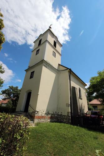 a building with a tower on top of a grass field at Gesztenyés Vendégház in Garáb