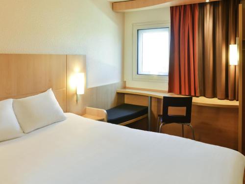a bedroom with a bed and a desk and a window at ibis Avignon Centre Gare in Avignon