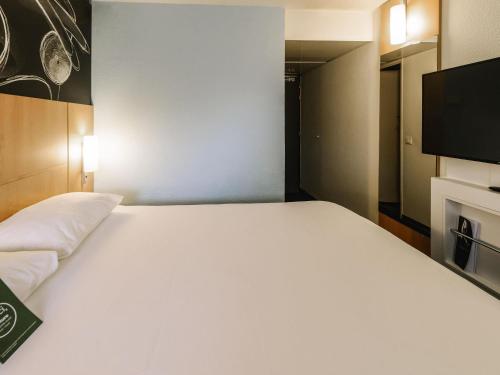 a large white bed in a room with a flat screen tv at ibis Avignon Centre Gare in Avignon