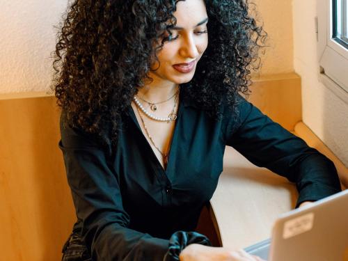a woman sitting at a table using a laptop computer at ibis Avignon Centre Gare in Avignon