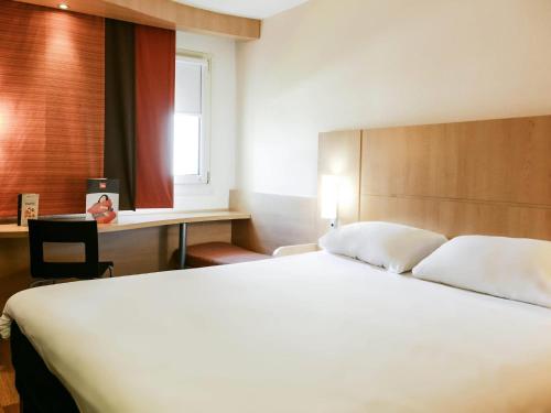 a bedroom with a large white bed and a desk at Hôtel Ibis Nevers in Nevers
