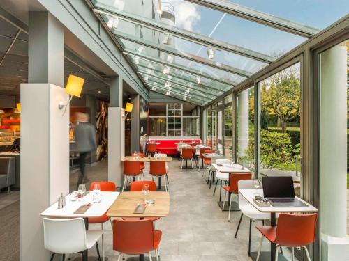 a restaurant with tables and chairs and windows at ibis Paris Meudon Velizy in Meudon