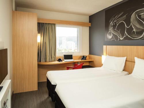 a hotel room with two beds and a desk at ibis Paris Meudon Velizy in Meudon