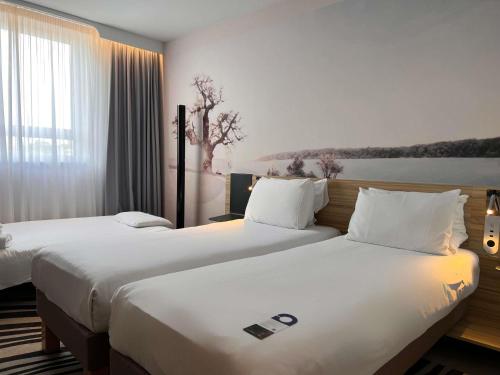 two beds in a hotel room with white sheets at Novotel York Centre in York