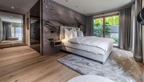 a bedroom with a large bed and a stone wall at Chalet Pfarriweg Modern luxury in Sankt Anton am Arlberg