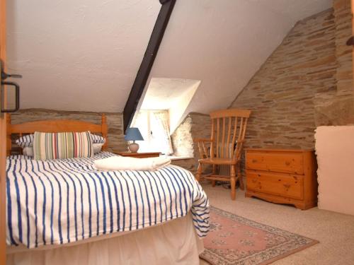 a bedroom with a bed and a chair in a attic at 3 Bed in Boscastle 75145 in Boscastle
