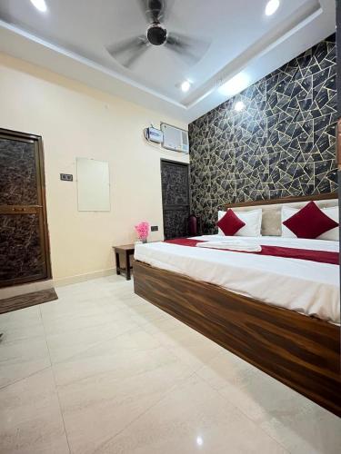 a bedroom with a large bed with red pillows at Raghukulam By R K Palace Ayodhya Dham in Ayodhya
