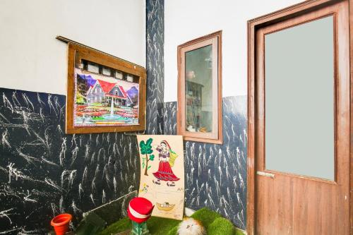 a room with paintings on the wall and a door at Super Hotel O Prayag Hotel in Ludhiana