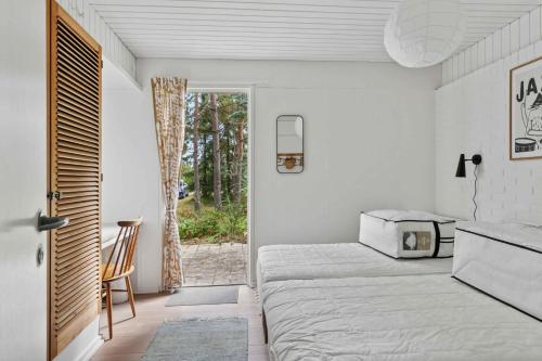 ein Schlafzimmer mit einem Bett und einer Tür zu einer Terrasse in der Unterkunft Cozy Cottage On Natural Plot in Gudmindrup