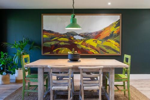 a dining room table with chairs and a painting on the wall at No.3 Long Barn in Wangford