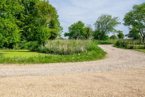 a gravel road leading into a field with trees at No.3 Long Barn in Wangford