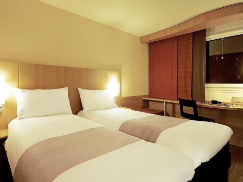 a hotel room with two beds and a window at ibis Le Puy-en-Velay Centre in Le Puy en Velay