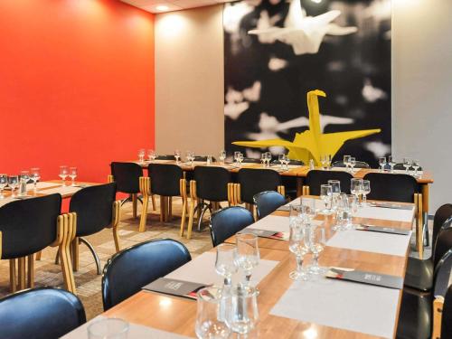 a conference room with tables and chairs and a painting at ibis Le Puy-en-Velay Centre in Le Puy en Velay