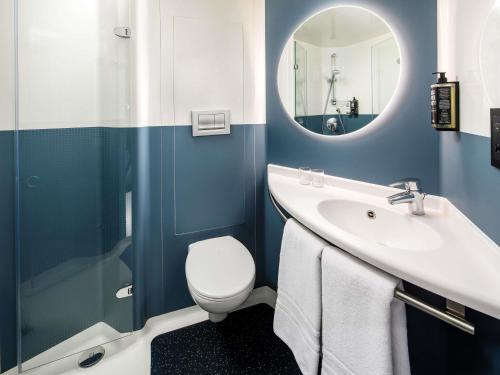 a bathroom with a sink and a toilet and a mirror at ibis London Greenwich in London