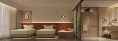 a bedroom with two beds and a chair and a mirror at Hilton Garden Inn Songyuan Ningjiang in Songyuan