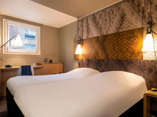 a hotel room with two beds and a window at ibis Paris Alesia Montparnasse in Paris