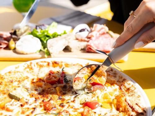 a person is cutting a pizza with a spoon at ibis Bordeaux Centre Meriadeck in Bordeaux