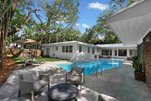 a backyard with a pool and chairs and a house at Memory Lane Cozy Home with Pool Lush South Miami in Miami