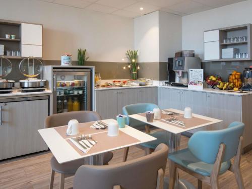 a kitchen with two tables and chairs and a kitchen with a counter at Mercure Nice Marché Aux Fleurs in Nice