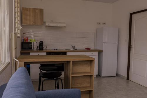 a kitchen with a table and a refrigerator at Cocon Montabo - logement tout équipé avec climatisation et Wi-Fi - à seulement 5 min de la plage in Cayenne