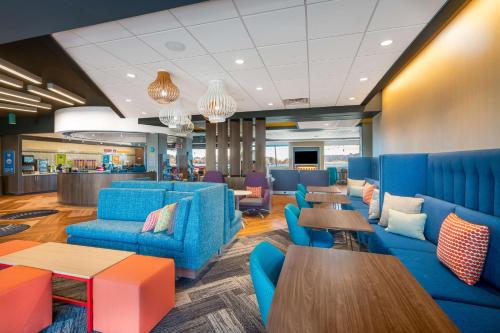 a waiting room with blue chairs and tables at Tru By Hilton Savannah Airport in Savannah