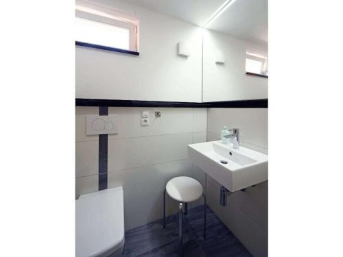 a white bathroom with a sink and a stool at One-bedroom apartment in Bernshausen